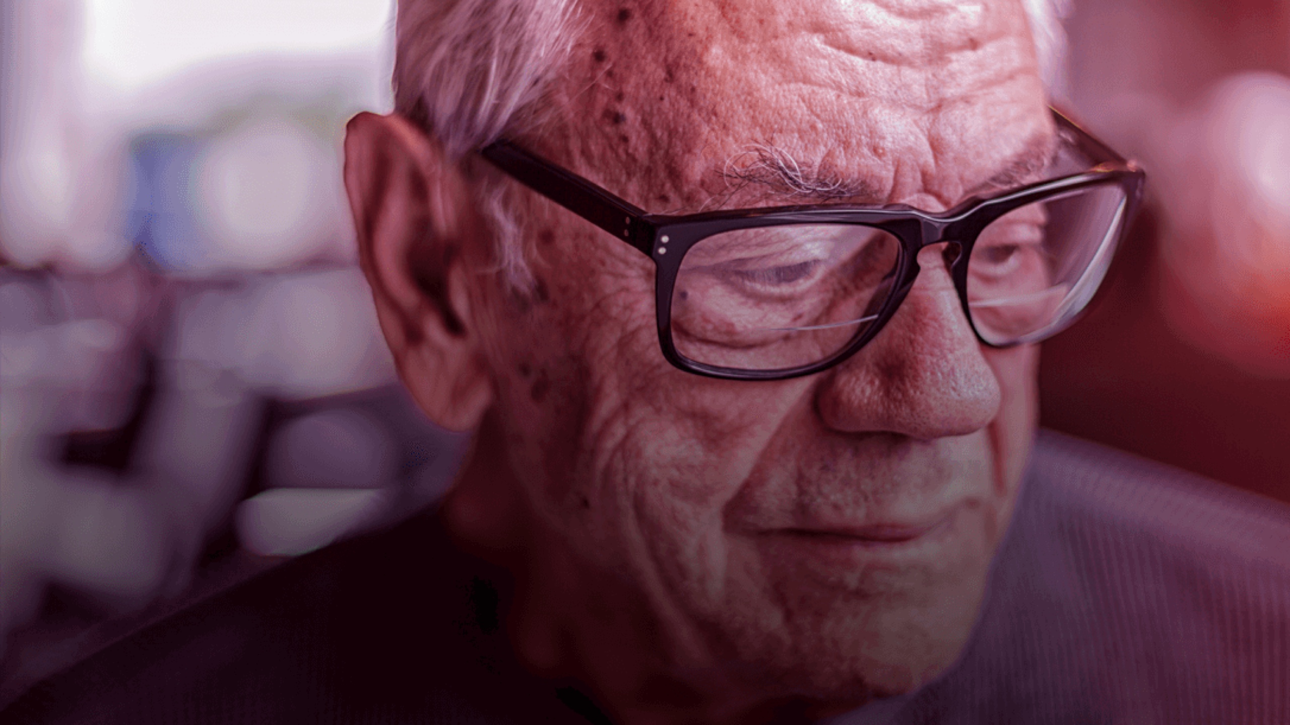 Image of elderly gentleman wearing glasses looking down