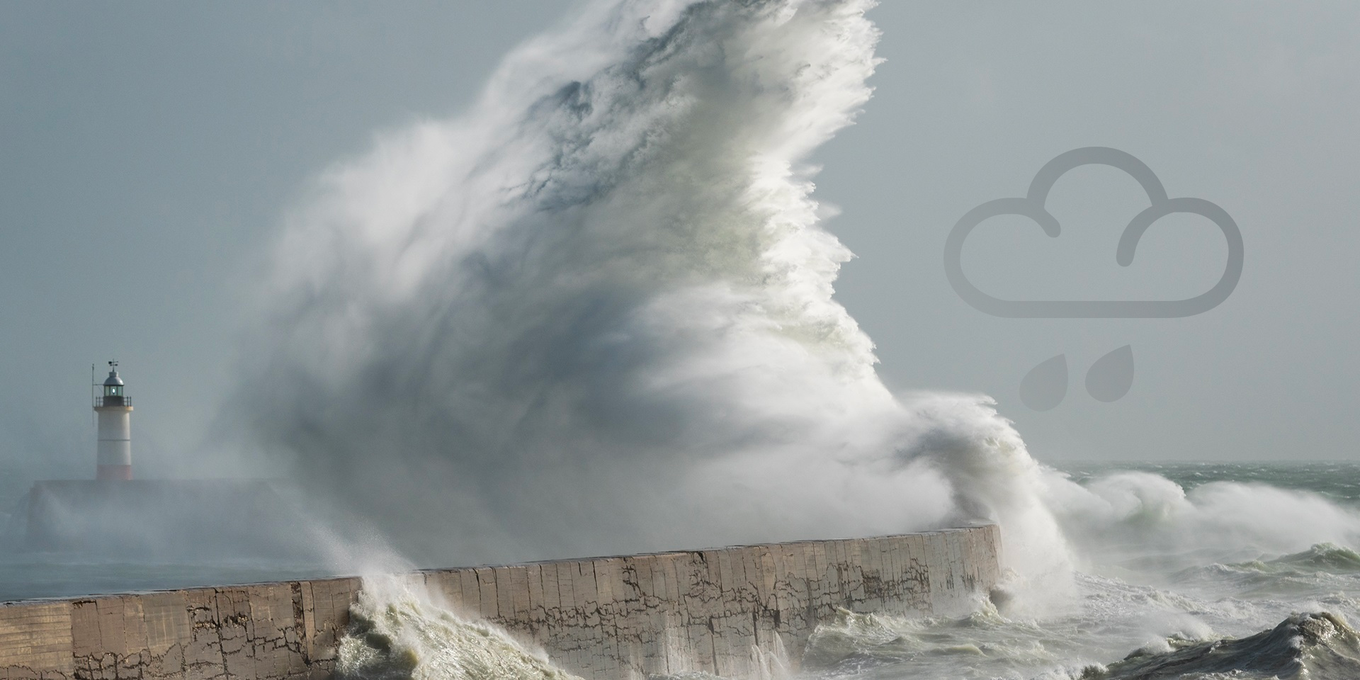 Stormy seas causing huge wave to batter the land next to a lighthouse